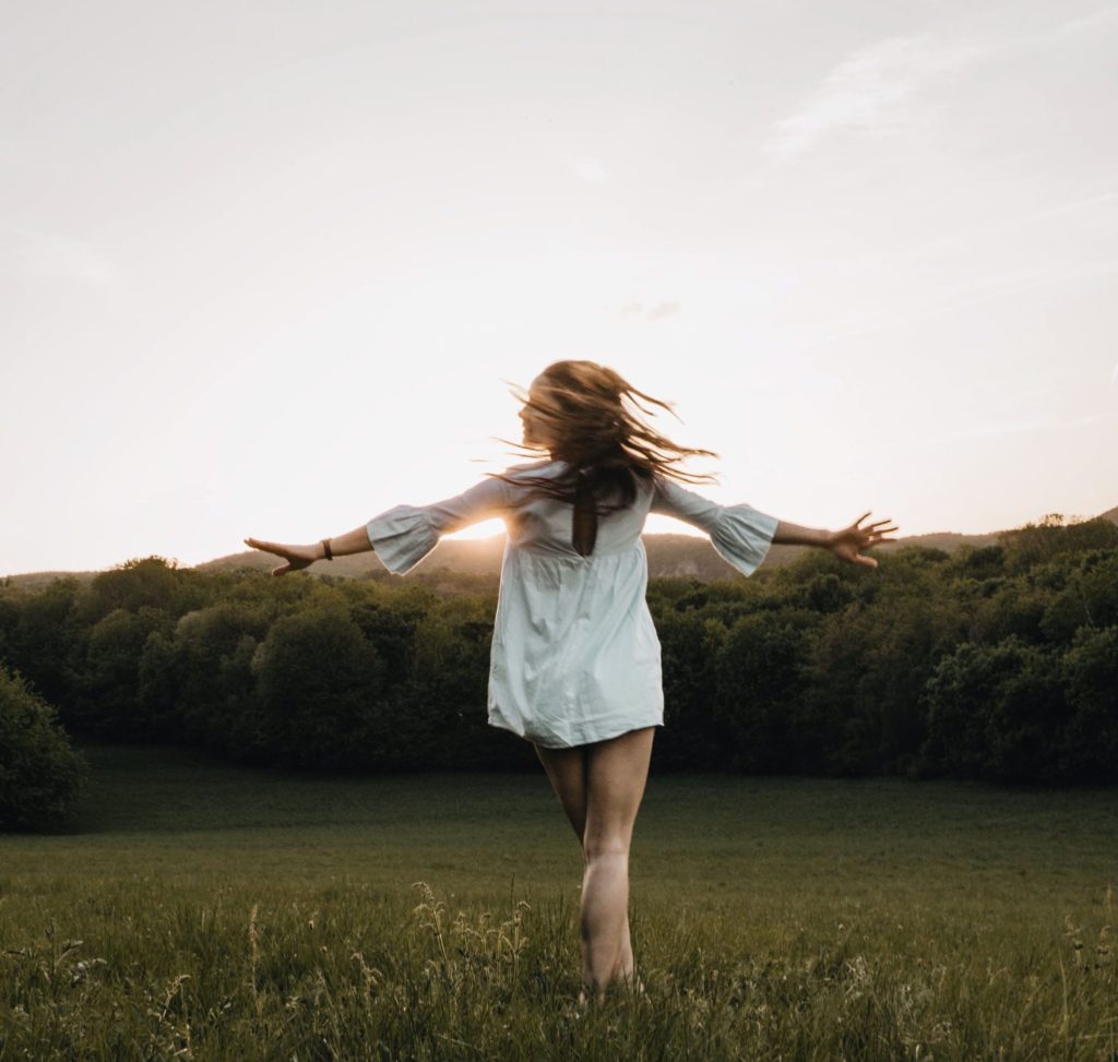 Woman happy and spinning in a field of grass